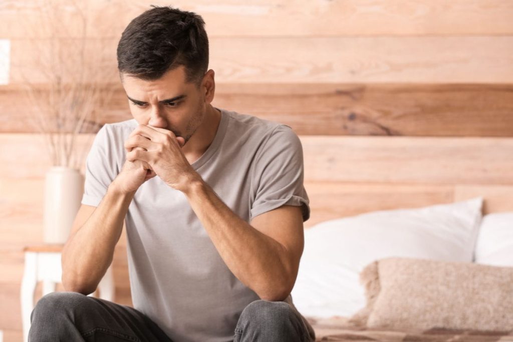 man with depression sits alone in his bedroom